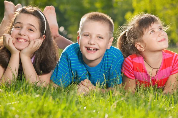 Três crianças felizes na grama — Fotografia de Stock