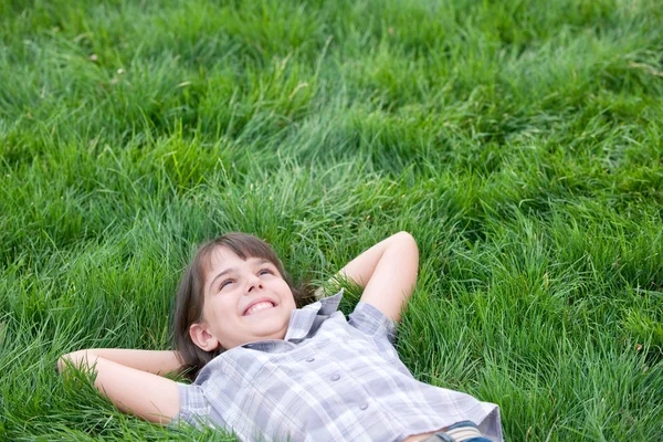 Menina feliz deitado na grama — Fotografia de Stock