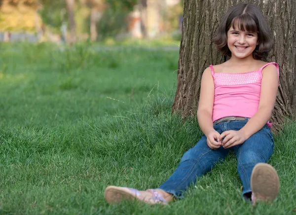 Dziewczyna siedzi przed drzewa — Zdjęcie stockowe