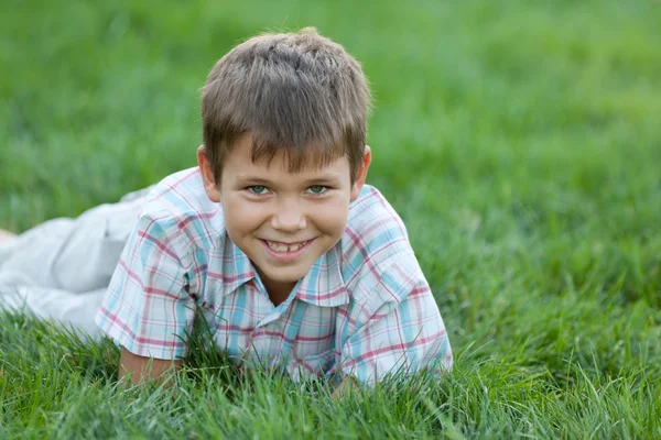 Улыбающийся ребенок на зеленой траве — стоковое фото