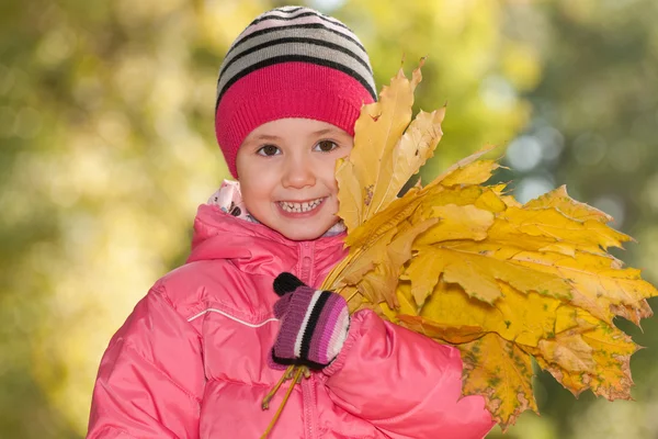 Lycklig liten flicka med gula blad — Stockfoto