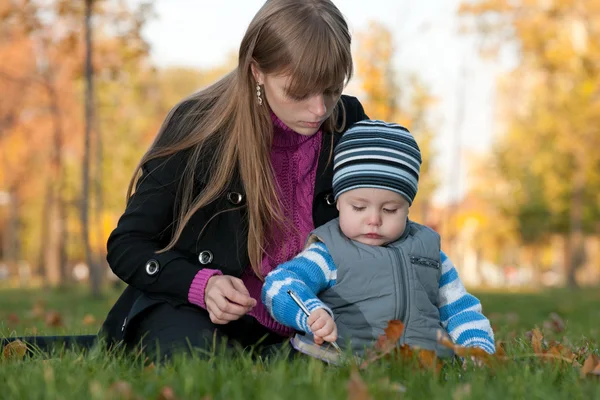 Mom は、秋の公園で彼女の息子を教えています。 — ストック写真