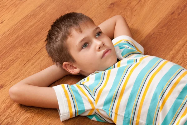 Portrait d'un garçon réfléchi aux grands yeux gris couché sur le woo — Photo