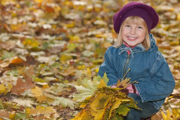 Laughing little girl with yellow leaves — Stock Photo, Image