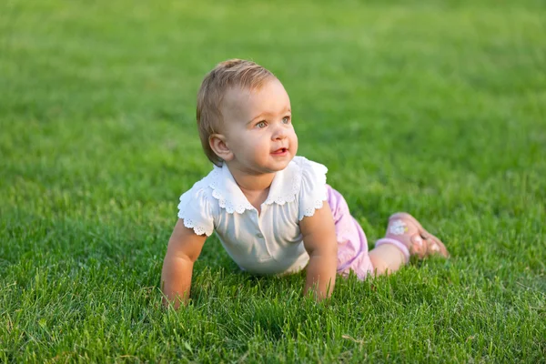 Überraschtes Kleinkind liegt im Gras — Stockfoto