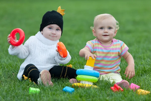 Portrét dvou malých holčičkách na trávě — Stock fotografie