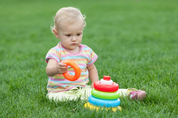 Allvarliga liten flicka på gräset — Stockfoto