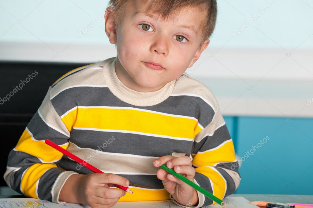 Confident little boy is sitting at the desk