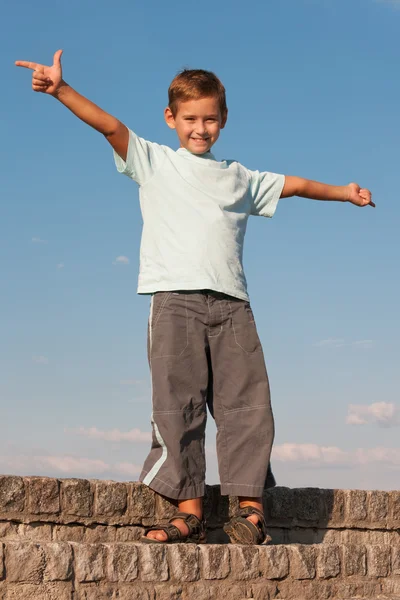 Gelukkige jongen staande tegen de hemel — Stockfoto