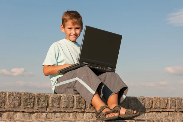 Gülen çocuk tutan bir dizüstü bilgisayar — Stok fotoğraf