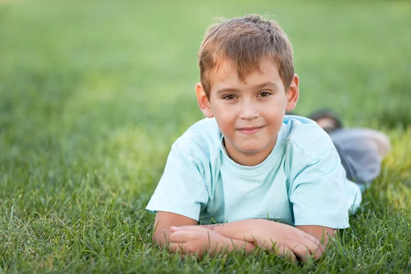 陽気な男の子、芝生の上に横たわる — ストック写真