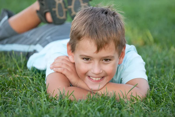 Detailní portrét smějící se chlapce na trávě — Stock fotografie