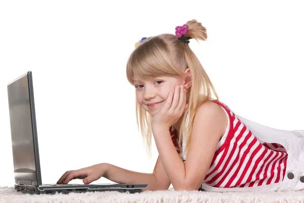 Mosolygó lány feküdt a vastag szőnyeg laptop tanul — Stock Fotó