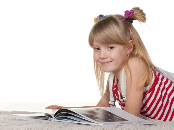 微笑女孩白色的厚厚地毯上阅读 — 图库照片
