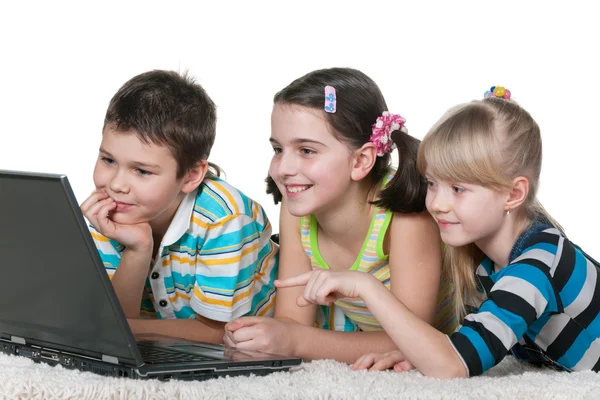 Drei Kinder lesen Internetinformationen mit einem Laptop — Stockfoto