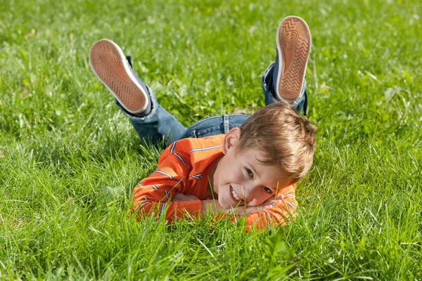 Gülümseyen çocuk çimenlerde yatıyor. — Stok fotoğraf