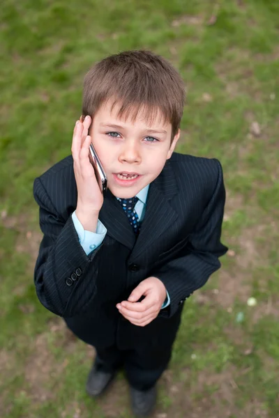 Серйозний хлопчик у костюмі, що говорить через мобільний — стокове фото
