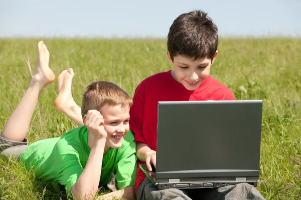 Twee jongens met laptop op het gras — Stockfoto