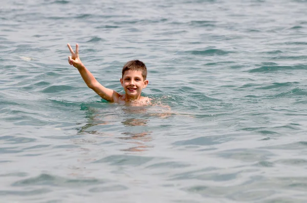 A swimming boy is holding his thumb up — Stock Photo, Image