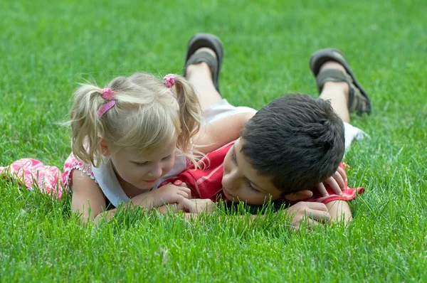 En pojke och en liten flicka på gräset — Stockfoto