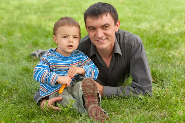 Портрет отца и сына на фоне зеленой травы — стоковое фото