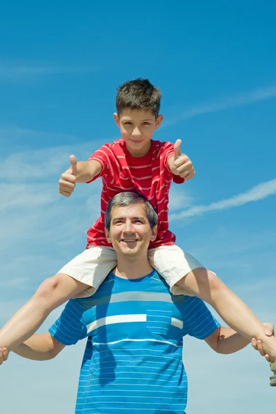 Kind in een rode shirt zittend op zijn vader — Stockfoto