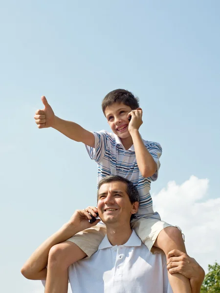 Отец и его сын разговаривают по мобильному телефону. — стоковое фото