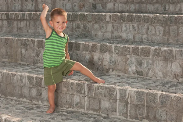 Улыбающийся мальчик на каменных ступеньках — стоковое фото