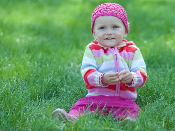 Kid in pink sitting on the green meadow — Stock Photo, Image