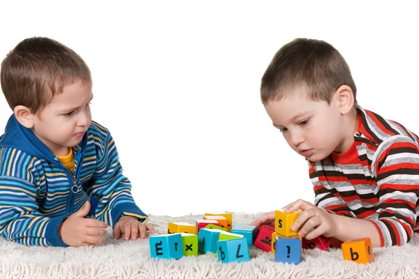 Irmãos jogando blocos no tapete — Fotografia de Stock