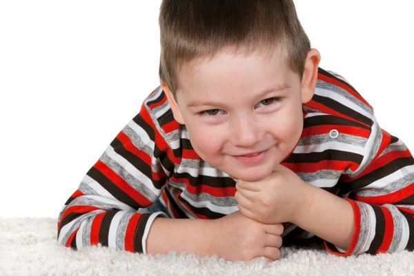 Usměvavý chlapec na bílý hustý koberec — Stock fotografie