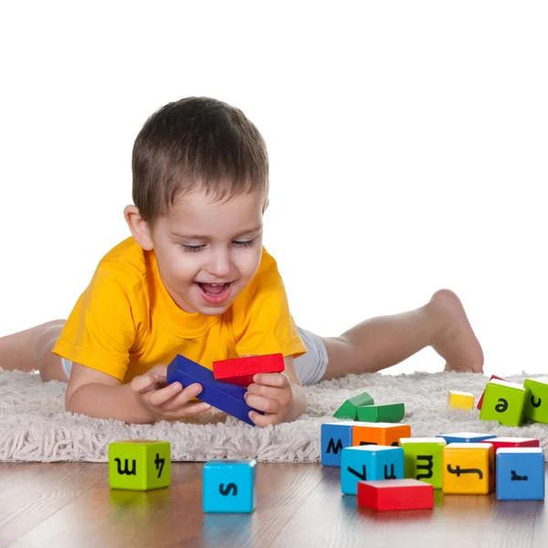 Kleine jongen speelgoed spelen op het tapijt — Stockfoto