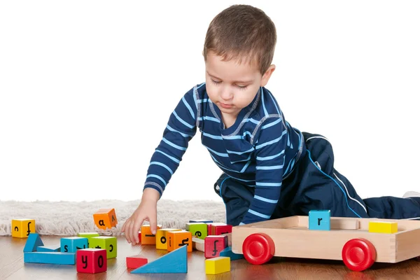 Маленький мальчик играет в блоки на ковре — стоковое фото