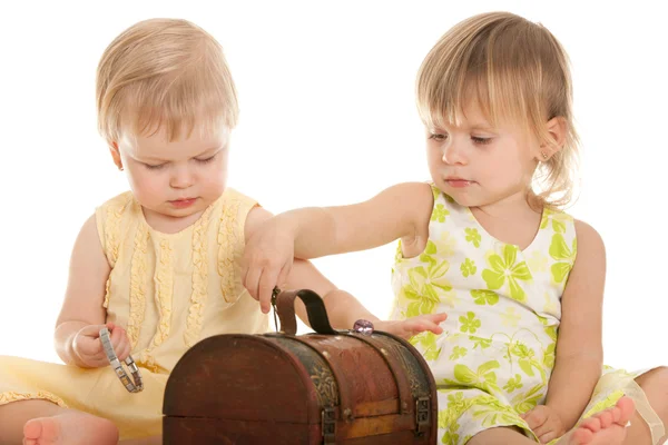 Две маленькие блондинки играют с деревянным сундуком — стоковое фото