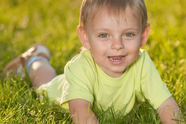 Смешной маленький мальчик лежит на зеленой траве — стоковое фото
