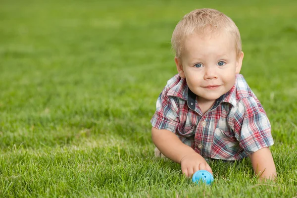 Grappige kleine jongen op het groene gras — Stockfoto