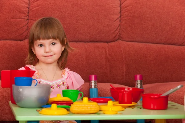 Lächelndes kleines Mädchen spielt am Tisch — Stockfoto