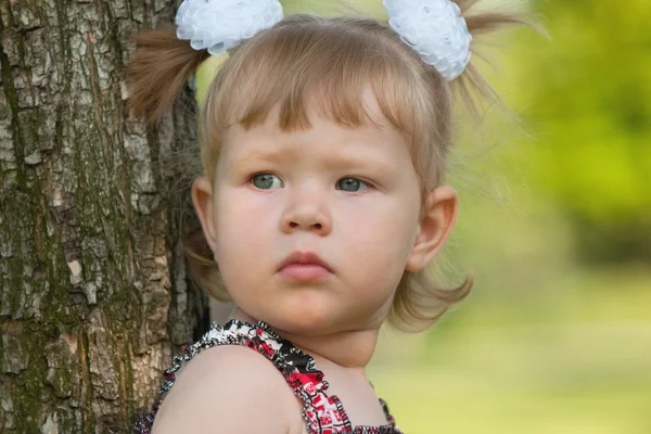 Продумана маленька дівчинка біля дерева — стокове фото