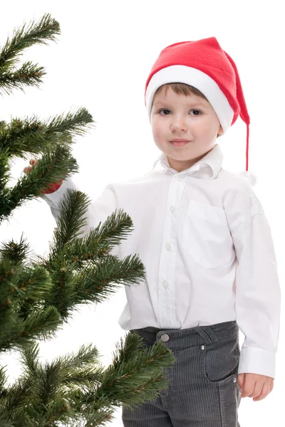 Niño guapo en el sombrero de Navidad que adorna el árbol de año nuevo —  Fotos de Stock