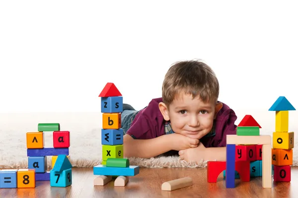 Маленький мальчик на полу рядом с игрушками — стоковое фото