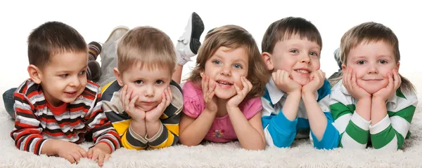 Пять детей лежат на ковре Лицензионные Стоковые Изображения