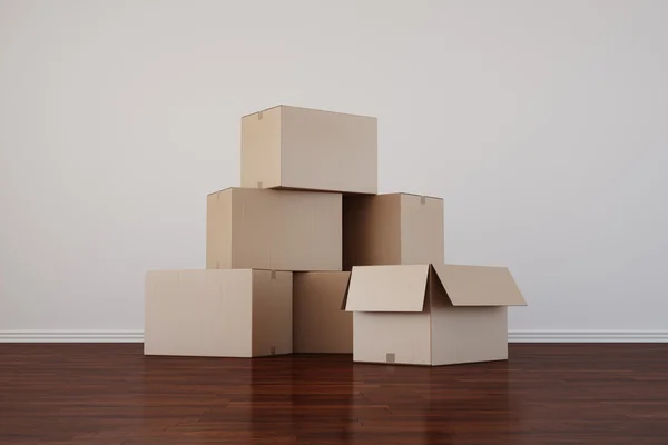 Κουτιά από χαρτόνι σε άδειο δωμάτιο με σκούρα δάπεδο — Φωτογραφία Αρχείου
