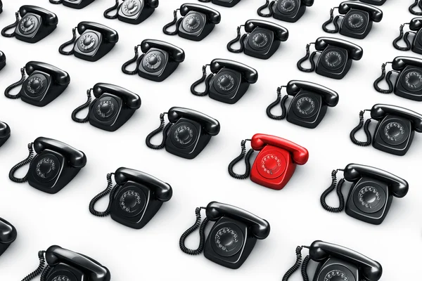 Teléfono rotativo rojo rodeado de teléfonos negros — Foto de Stock