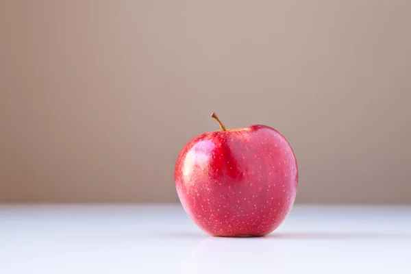 Manzana roja en blanco con fondo marrón —  Fotos de Stock