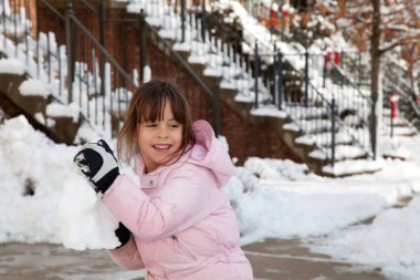 Little Girl Throwing a Giant Snow Ball clipart