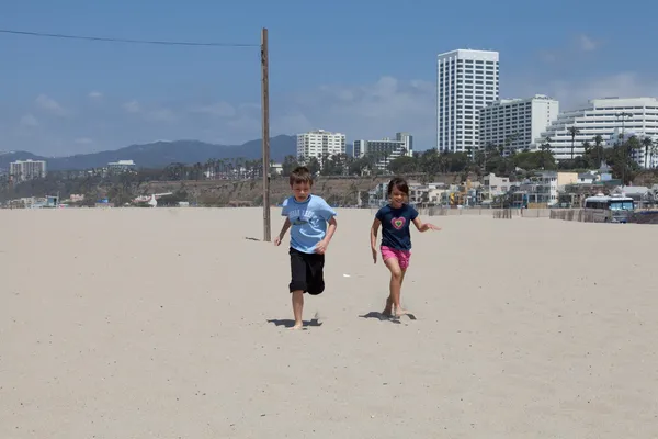 Mädchen und Junge rennen am Strand — Stockfoto