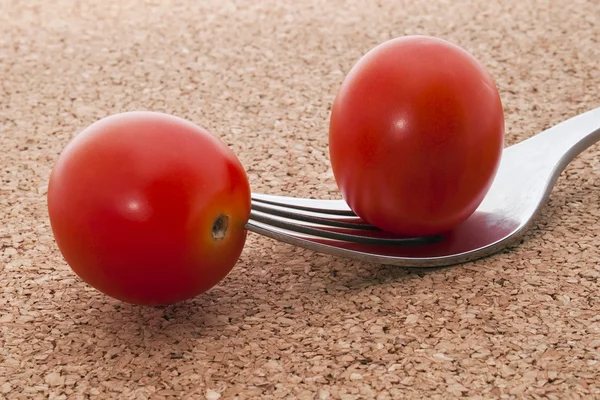 कॉर्क पार्श्वभूमीवर काटा वर दोन लहान लाल टोमॅटो — स्टॉक फोटो, इमेज