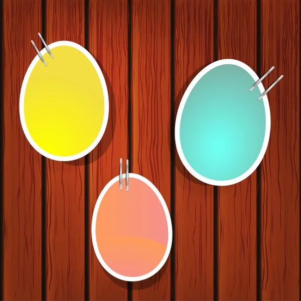 Easter eggs on pins on the wooden wall — Stock Vector