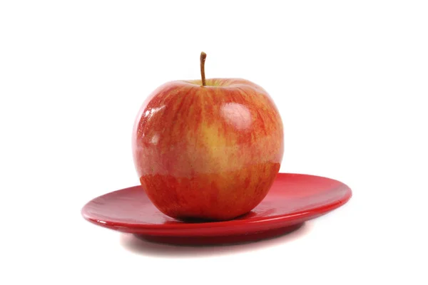 Mela fresca su un piatto rosso isolato su bianco — Foto Stock