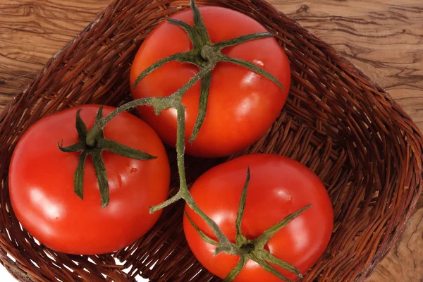 Три свежих красных помидора на тканой тарелке — стоковое фото